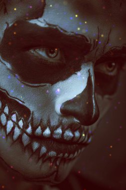 Cadılar Bayramı. Karanlık bir arka planda kafatası makyajı yapmış şeytani yakışıklı bir adamın yakın plan portresi. Dia de los muertos. Ölülerin Günü. 