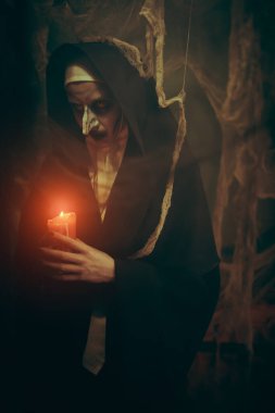 Korku ve Cadılar Bayramı. Terk edilmiş kilisede elinde mumla duran lanetli bir rahibenin portresi..