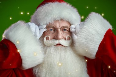 Geleneksel bir Noel Baba portresi. Kameraya bakıyor. Yıldızlı yeşil stüdyo geçmişi. Noel ve Yeni Yıl.