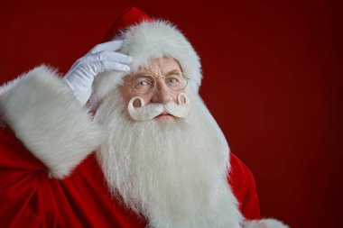 Geleneksel bir Noel Baba portresi. Kameraya bakıyor. Fotokopi alanı olan kırmızı stüdyo. Noel ve Yeni Yıl.