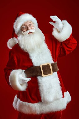 Kameraya bakan nazik bir Noel Baba portresi. Kırmızı stüdyo geçmişi. Noel ve Yeni Yıl.