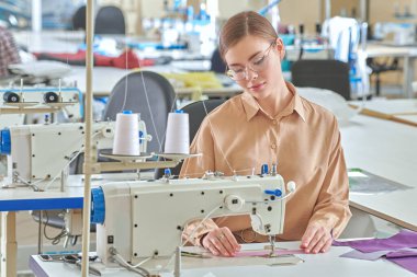 Dikiş atölyesi. Genç, güzel bir terzi dikiş makinesinde çalışıyor. Moda endüstrisi. Moda tasarımcısı.