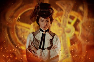 Kendinden emin bir steampunk kadın mucidi dönen mekanizmaların arka planında duruyor. Eski tarz. Sanayi devrimi. 19. yüzyılın icatları..