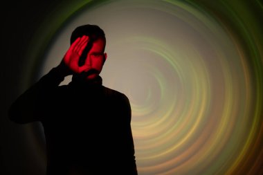 Bir adam ayakta duruyor, kırmızı güneş ışınlarından saklanarak bir kara deliğin ya da bir zaman geçidinin ışık çemberlerinin arka planında saklanıyor. Sanat fotoğrafçılığı. Bilim kurgu romanı. Boşluğu kopyala. 