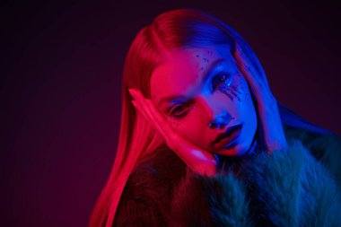 Parlak sanatsal makyaj. Parlak parlak makyajlı güzel bir kızın portresi, parlak gözyaşları ve karışık renkli neon ışıkta poz veren sarı saçlar. Güzellik trendleri ve moda. Boşluğu kopyala. 