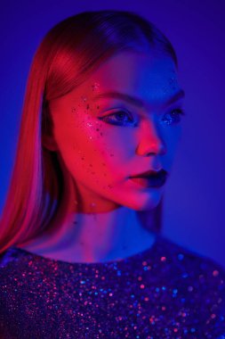 Parlak makyajlı şık sarışın bir kızın portresi ve parlak bir gece elbisesi karışık mavi-kırmızı poz veriyor. Parıltı, moda ve tarz. Gece kulübü, disko, neon ışıklar.. 