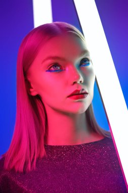 Göz kamaştırıcı parlak stil, sanatsal makyaj. Parlak makyajlı, neon lambaların ışığında sarı saçlı güzel bir manken kızı portresi. Stüdyo çekimi. Güzellik ve makyaj.. 