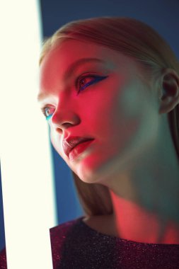 Göz kamaştırıcı parlak stil, sanatsal makyaj. Parlak makyajlı, neon lambaların ışığında sarı saçlı güzel bir manken kızı portresi. Stüdyo çekimi. Güzellik ve makyaj.. 