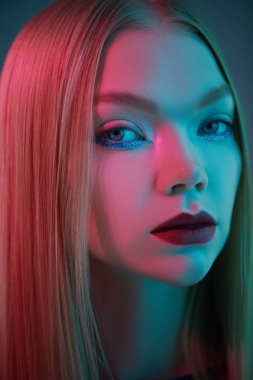 Göz kamaştırıcı parlak stil, sanatsal makyaj. Parlak makyajlı, sarı saçlı, neon lambalı güzel bir manken kızı portresi. Stüdyo çekimi. Güzellik ve makyaj.. 