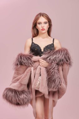 Zarif makyajlı, pahalı bir kürk manto ve siyah dantel sutyenle poz veren sevimli genç bir kadın. Kürk manto moda.. 