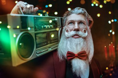 Noel ve yeni yıl için eğlenceli bir parti. Modern bir Noel Baba zarif üç parçalı bir takım elbise içinde elinde bir teyple sihirli bir Noel ışığı ile dans eder..