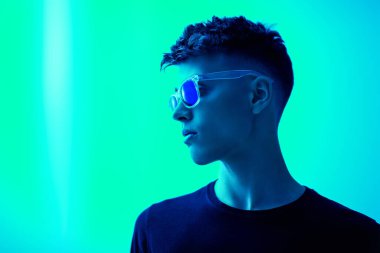 Siyah günlük kıyafetler ve parlak mavi bir arka planda poz veren gözlüklü bir adam. Erkek modası ve tarzı. Boşluğu kopyala.