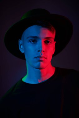 Siyah günlük kıyafetler giymiş yakışıklı bir esmer adamın sanat portresi. Karmaşık ışıklandırmalı koyu bir arka plan. Gençler. Erkek güzeli.. 