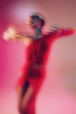 Göz kamaştırıcı bayan dansçı, parlak mücevherleri olan zarif kırmızı elbiseler içinde Latin dansı yapıyor. Moda ve güzellik. Bale gösterisi. Bulanık efektli stüdyo resmi.