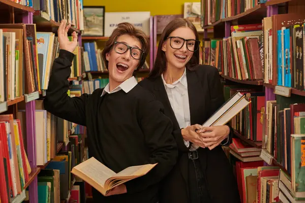 Joyful modern students in black and white uniform with books in a library. Modern generation. Education.