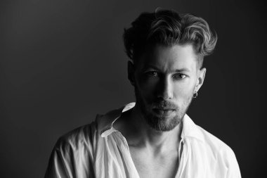 Siyah beyaz, beyaz, siyah arka planda beyaz tişörtlü, olgun bir adamın resmi. 19. yüzyılın sonlarından 20. yüzyılın başlarına kadar yaşamış bir adamın tarihi portresi. Erkek güzeli.. 