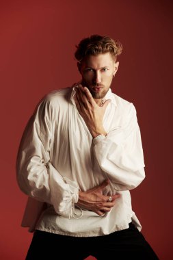 Beyaz, klasik gömlekli, kırmızı saçlı, yakışıklı, olgun bir adam, geniş kollu, bordo bir arka planda poz veriyor. 19. yüzyılın sonlarından 20. yüzyılın başlarına kadar yaşamış bir adamın tarihi portresi. Erkek güzeli.. 