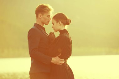 Şık giyimli sevgili çift gün batımında birbirlerine nazikçe bakarak deniz kenarında dururlar. Tarihi aşk romanı. Sevgi dolu bir ilişki. 19. yüzyıl tarzı.