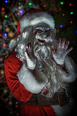 Noel, Yeni Yıl ve Cadılar Bayramı. Korkunç bir zombi Noel Baba portresi kanlı sakallı ve gözü yanan, kameraya bakıp şeytanca gülen. Koyu arkaplan. 