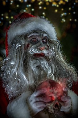 Cadılar Bayramı ve Noel. Korkunç ve havalı Noel Baba zombi bir kafatası tutuyor. Gecenin arka planı, kuzey ışıklarıyla yıldızlı gökyüzü..