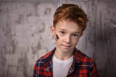 Yakışıklı bir çocuğun portresi, modaya uygun saç stili, şık günlük giysiler içinde, grunge arka planda poz veriyor. Çocuk modası.