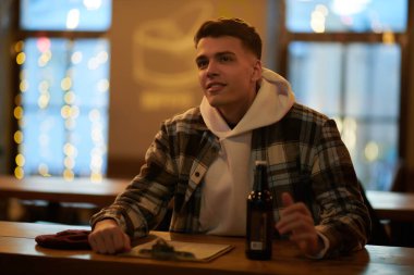 Yakışıklı genç adam bir barda rahatlıyor ve bira içiyor. Sıcak atmosfer ve pencerelerde yanıp sönen ışıklar.