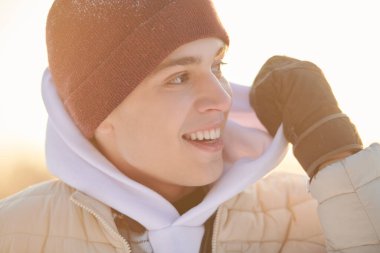 Açık havada duran ve geniş bir şekilde gülümseyen kışın giydiği mutlu yakışıklı bir adamın yakın plan portresi. Duygular. Mutlu insanlar konsepti.