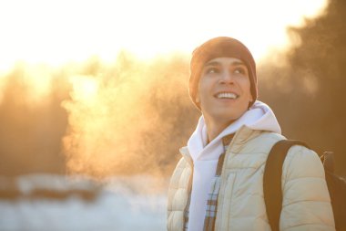 Duygular. Parkta durmuş gülümseyen, kışlık giysiler içindeki yakışıklı bir adamın portresi. Mutlu insanlar konsepti. Boşluğu kopyala.