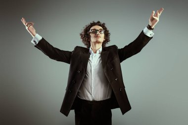 İlham. Kıvırcık saçlı ve klasik siyah takım elbiseli heybetli esmer bir adam kollarını yana ve yukarı kaldırmış, ilham doludur. Zafer ışıklarıyla. Kondüktör sahnede.