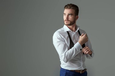 Klasik şık giyimli yakışıklı bir adamın portresi. İyi akşamlar erkek modası. Fotokopi alanı olan gri bir arkaplanda stüdyo resmi.