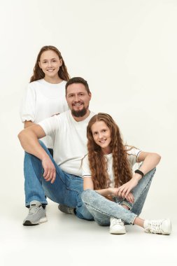Mutlu gülümseyen bir babanın iki sevgili kızıyla tam boy portresi. Mutlu aile kavramı. Beyaz arkaplanda stüdyo portresi.