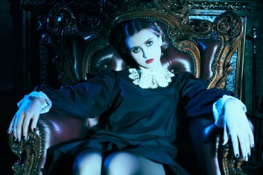 Kasvetli bir kalede, koltukta oturan, katı siyah elbiseli, beyaz yakalı, tuhaf, esmer bir kızın portresi. Mistik gotik roman, korku. Addams Aile Stili. 