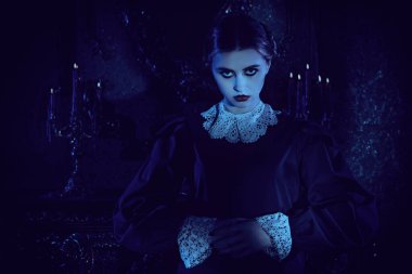 Siyah gözlü, koyu siyah elbiseli, beyaz yakalı çekici bir esmer kızın gotik portresi. Geceleri kasvetli, eski bir malikanede duruyor. Addams Ailesi. Gotik roman, mistisizm..