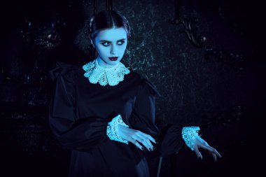 Mistik gotik roman. Kasvetli bir kalede ay ışığında dans eden, katı siyah elbiseli, beyaz yakalı çekici bir esmer kızın portresi. Addams Aile Stili. 