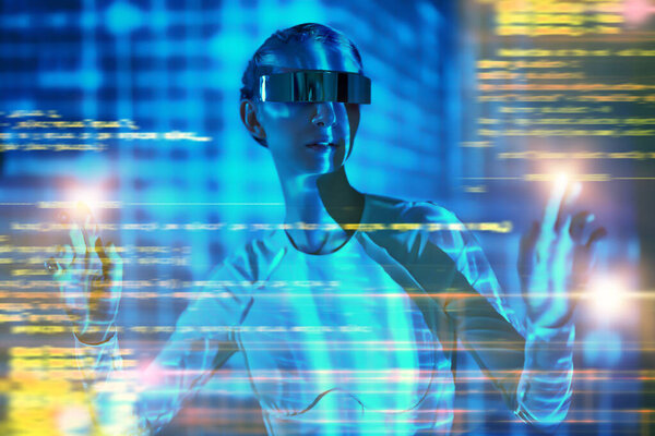 Cyberspace. Perfect cyber girl in futuristic glasses and overalls controls digital hologram while standing in neon blue light. Digital technologies of the future. VR games.