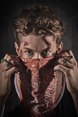 An aggressive determined man with wounds on his face and the bandana covering his face. Revolution. Action movie hero. clipart