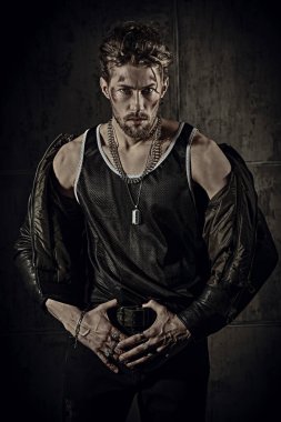 Yüzünde çizikler ve deri ceketli, beton bir duvarın karşısında kameraya güvenle bakan yakışıklı, vahşi bir adam. Aksiyon filmi, dedektif filmi..