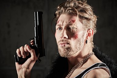 Kötü adam konsepti. Yüzünde morluklar ve yaralar olan, siyah bir arka planda duran ve kameraya agresif bir şekilde bakan sert bir erkek haydut vuruldu. Aksiyon filmi kahramanı.