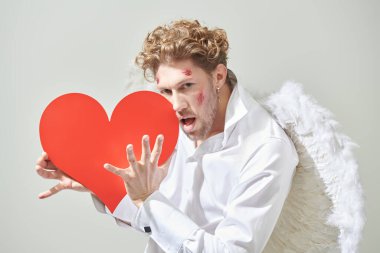 Cesur yakışıklı adam aşk tanrısı yüzünde yaralar olan aşk tanrısı ellerinde kırmızı bir kalp tutuyor. Aşk için savaş. Sevgililer Günü..