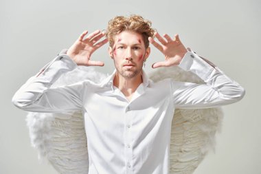 Fantezi kahramanı aşığı. Beyaz elbiseli, beyaz kanatlı, yüzünde yaraları olan çekici bir aşk meleği kameraya bakıyor. Aşk Tanrısı Aşk Tanrısı. Sevgililer Günü.