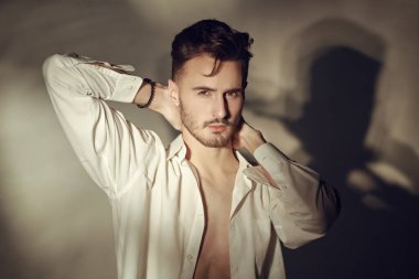 Klasik beyaz gömlekli yakışıklı bir adamın portresi gri stüdyo arka planına karşı. Klasik moda ve erkek güzelliği. 