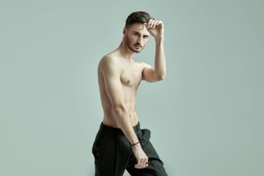 Gri stüdyo arka planında çıplak gövdesi olan yakışıklı esmer bir adamın portresi. Erkek sağlığı ve güzelliği. Boşluğu kopyala.