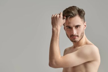 Stüdyo arka planında çıplak gövdesi olan yakışıklı, esmer bir adamın portresi. Erkek sağlığı ve güzelliği. Boşluğu kopyala.