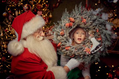 Güzel bir Noel ortamında çelengi olan nazik Noel Baba 'ya sahip küçük bir kız. Mutlu Noeller ve mutlu yıllar.!