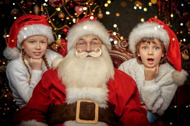 Güzel bir Noel ortamında Noel Baba 'nın yanında iki neşeli çocuk. Noel ve Yeni Yıl Kutlaması. 