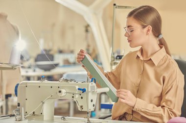 Dikiş makinesinde çalışan genç ve güzel bir terzinin fotoğrafı. Moda endüstrisi. Moda tasarımcısı. Dikiş atölyesi. 