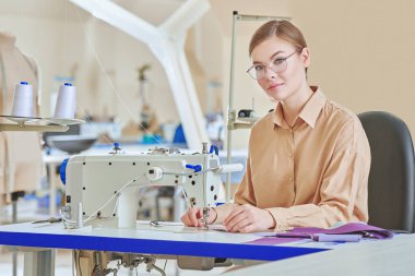 Giysi imalatı. Dikiş atölyesinde çalışan genç ve güzel bir kadının mesleği. Moda endüstrisi. 