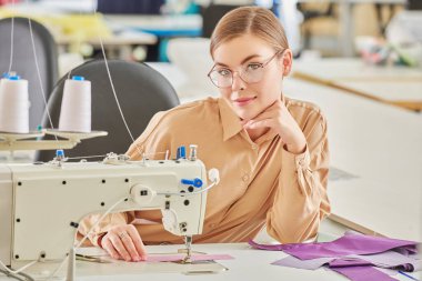 Güzel bir genç kız terzi dikiş atölyesinde yeni bir ürün dikiyor. Moda endüstrisi. Giysi imalatı.