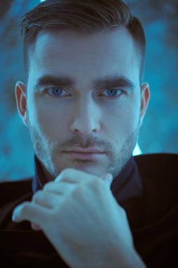 Neon lambaların arkasında duran yakışıklı, cesur bir adamın fotoğrafı. Uzay fantezisi. Bilim kurgu, Siberpunk teması.