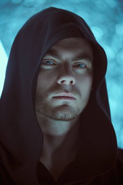 Kafasında bir başlık olan siyah bir bornoz giymiş cesur bakışlı vahşi bir adam neon lambaların ışığında duruyor. Fantezi kahramanı. Uzay ve gelecek dünya hakkında bilim kurgu. Sanal tema.